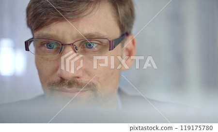 Businessman with glasses looking intently obscured partially by a translucent surface of laptop. Business people concept Businessman with glasses looking intently obscured partially by a translucent surface of laptop. Business people concept 119175780