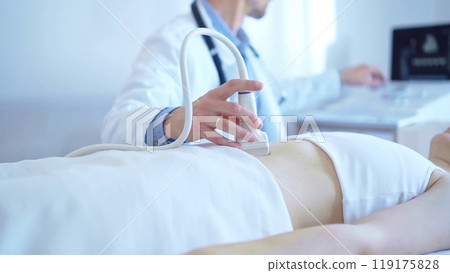 Doctor man wearing a white coat using an ultrasound equipment on a female patient lying down in clinic cabinet. Preventive therapy in medicine 119175828