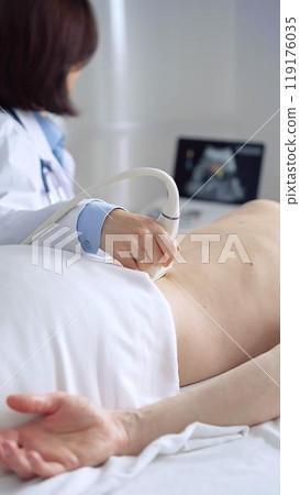 Doctor performing ultrasound examination on patient's back 119176035