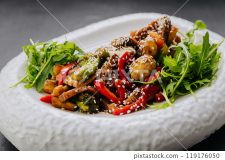Delicious vegetable salad with arugula, sesame, and bell peppers, served in an elegant white bowl Delicious vegetable salad with arugula, sesame, and bell peppers, served in an elegant white bowl 119176050