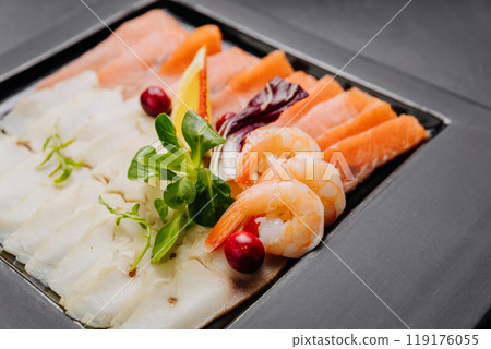 Gourmet seafood platter with fresh salmon, shrimp, and white fish fillet served with herbs and lemon Gourmet seafood platter with fresh salmon, shrimp, and white fish fillet served with herbs and lemon 119176055