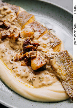 Whole roasted fish with creamy mushroom sauce and mashed potatoes on a ceramic plate Whole roasted fish with creamy mushroom sauce and mashed potatoes on a ceramic plate 119176060