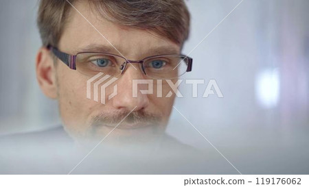 Businessman with glasses looking intently obscured partially by a translucent surface of laptop. Business people concept Businessman with glasses looking intently obscured partially by a translucent surface of laptop. Business people concept 119176062