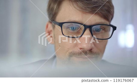 Businessman with glasses looking intently obscured partially by a translucent surface of laptop. Business concept Businessman with glasses looking intently obscured partially by a translucent surface of laptop. Business concept 119176067