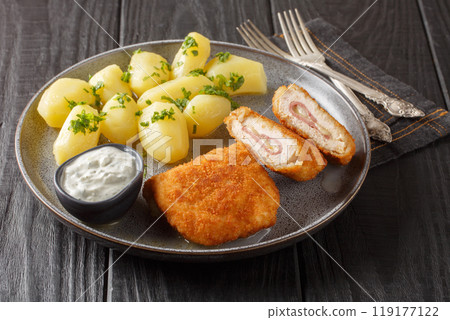 Tasty Chicken Cordon Bleu served with new potatoes and cream sauce closeup on the plate. Horizontal Tasty Chicken Cordon Bleu served with new potatoes and cream sauce closeup on the plate. Horizontal 119177122