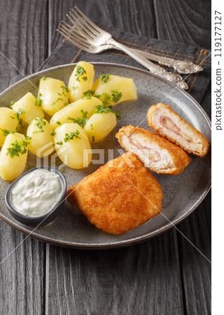 French traditional cuisine chicken cordon bleu with new potatoes and cream sauce closeup on the plate. Vertical French traditional cuisine chicken cordon bleu with new potatoes and cream sauce closeup on the plate. Vertical 119177127