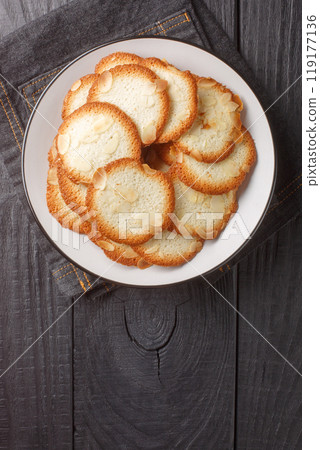 Almond tuiles a French cookie with allure closeup on the plate. Vertical top view Almond tuiles a French cookie with allure closeup on the plate. Vertical top view 119177136