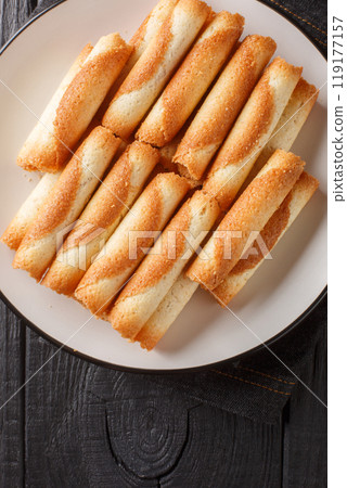 Cigarette Russes or Russian cigarettes are homemade thin cookies closeup on the plate. Vertical top view 119177157