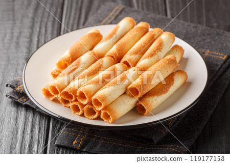 French sweet thin wafer tubes called Russian cigarettes close-up in a plate. Horizontal 119177158