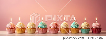 Colorful cupcakes with lit candles are displayed against a pink background, indicating an indoor celebration event marking of joy and celebrating. with free space 119177387