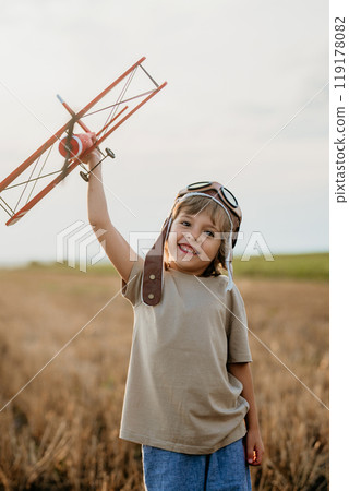 Handsome child boy running with wooden airplane. Kid dreaming to be pilot. 119178082