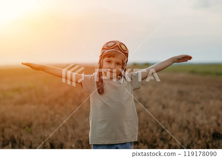 Happy Boy In Aviator Pilot Helmet Runs As Airplane On Nature Meadow, Outside 119178090