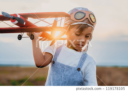 Smiling Interested Child Boy in Pilot Helmet Playing With Wooden Airplane. Smiling Interested Child Boy in Pilot Helmet Playing With Wooden Airplane. 119178105