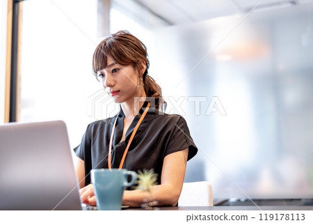 A woman working on a computer with a serious expression 119178113