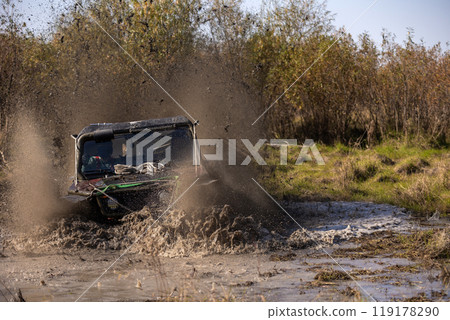 Off road buggy crossing water obstacle in a bog terrain making a lot of splashes 119178290