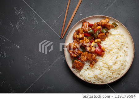 Kung pao chicken with peanuts and rice on a plate top view, traditional Chinese cuisine. Space for text Kung pao chicken with peanuts and rice on a plate top view, traditional Chinese cuisine. Space for text 119179594