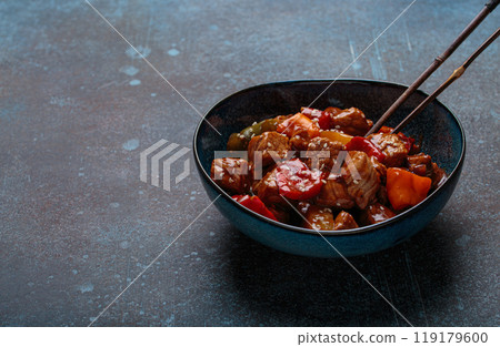 Sweet and sour pork with bell peppers and pineapple in a bowl, classic Chinese dish Sweet and sour pork with bell peppers and pineapple in a bowl, classic Chinese dish 119179600