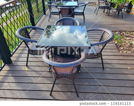 Outdoor cafe with brown tables with glass tops with a reflection of the sky. 119181113