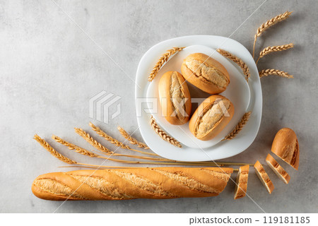 Baguette, French buns, and wheat ears on a marmoreal background. Baguette, French buns, and wheat ears on a marmoreal background. 119181185