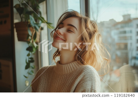 Serene woman enjoying morning light by window in cozy sweater Serene woman enjoying morning light by window in cozy sweater 119182640