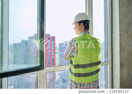 Male industrial worker in vest helmet on new residential or commercial construction site 119184137