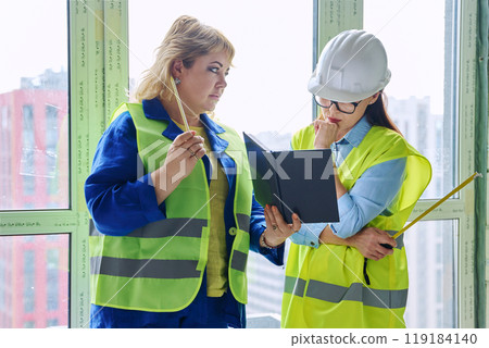 Two female industrial workers at construction site discussing work Two female industrial workers at construction site discussing work 119184140