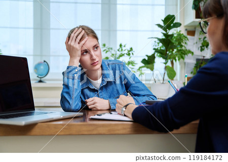 Sad upset young teenage female patient talking to professional mental therapist Sad upset young teenage female patient talking to professional mental therapist 119184172