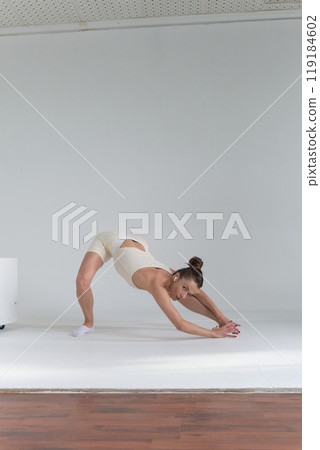 Female dancer in a beige outfit, holding a perfect backbend with one leg lifted, showcasing athleticism. Concept: Highlighting how dedication to physical training can enhance both mental and physical 119184602