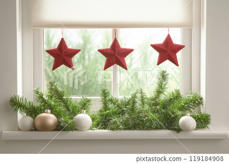 Red Christmas ornaments hanging on green branches beside a window with a snowy view outside. Concept of holiday decor Red Christmas ornaments hanging on green branches beside a window with a snowy view outside. Concept of holiday decor 119184908