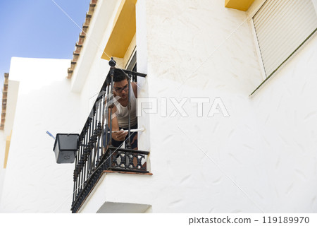 Caucasian man painting a house, perfect for home renovation and DIY projects Caucasian man painting a house, perfect for home renovation and DIY projects 119189970