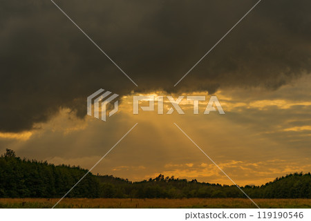 The light of the setting sun shining through the thick clouds 119190546
