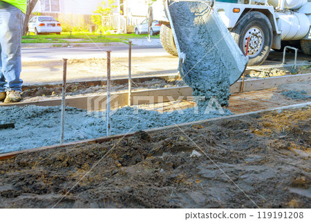 Concrete mixer truck pouring fresh concrete over reinforced bars for construction of new sidewalk Concrete mixer truck pouring fresh concrete over reinforced bars for construction of new sidewalk 119191208
