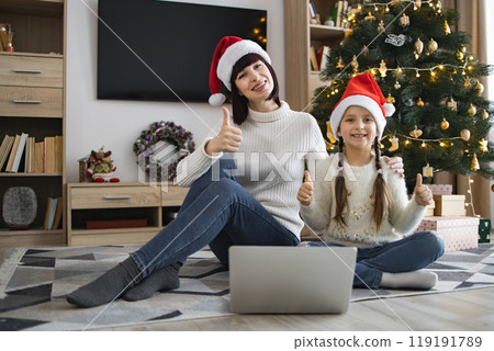 Mother and daughter celebrating Christmas together with computer Mother and daughter celebrating Christmas together with computer 119191789