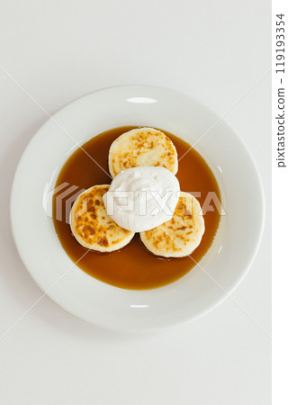 Enjoy fluffy pancakes topped with whipped cream and served with warm syrup that enhances their flavor 119193354