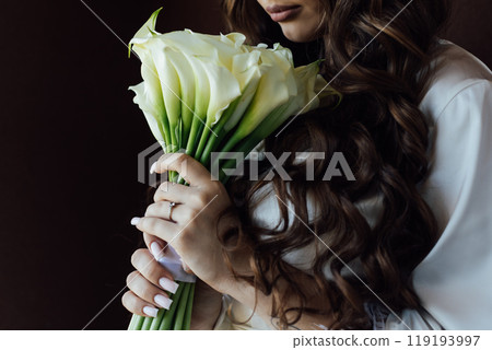Boudoir photo of a beautiful girl with long hair. Flowers in the hands of a beautiful woman. Boudoir photo of a beautiful girl with long hair. Flowers in the hands of a beautiful woman. 119193997