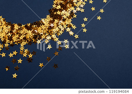 An arrangement of numerous gold stars placed on a blue background 119194084