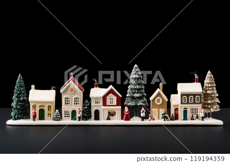Miniature winter village with various houses, snowy trees, and figurines on black background. Festive holiday decor 119194359
