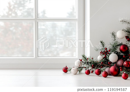 Red and silver Christmas ornaments on green branches beside a window with a snowy view outside. Concept of holiday decor 119194587