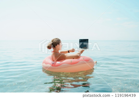Woman laptop sea. Freelancer woman in sunglases floating on an inflatable big pink donut with a laptop in the sea. People summer vacation rest lifestyle concept Woman laptop sea. Freelancer woman in sunglases floating on an inflatable big pink donut with a laptop in the sea. People summer vacation rest lifestyle concept 119196439