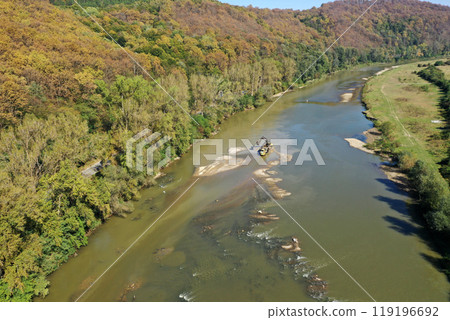 Aerial view of illegal exploitation of river sand and gravel with excavator on river bank 119196692