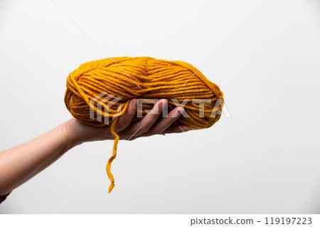 Woman holding red or orange wool ewes in knitting yarn on white background, Copy space. Hobby knitting concept 119197223