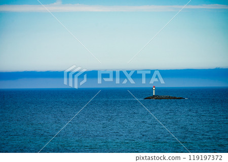 Seascape sandy beach with lighthouse on horizon Seascape sandy beach with lighthouse on horizon 119197372