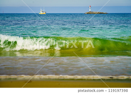 Seascape sandy beach with lighthouse on horizon Seascape sandy beach with lighthouse on horizon 119197398