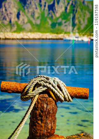 Old rusty mooring bollard with rope. Old rusty mooring bollard with rope. 119197598