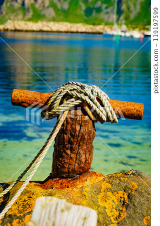 Old rusty mooring bollard with rope. Old rusty mooring bollard with rope. 119197599