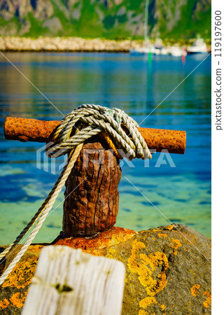 Old rusty mooring bollard with rope. Old rusty mooring bollard with rope. 119197600