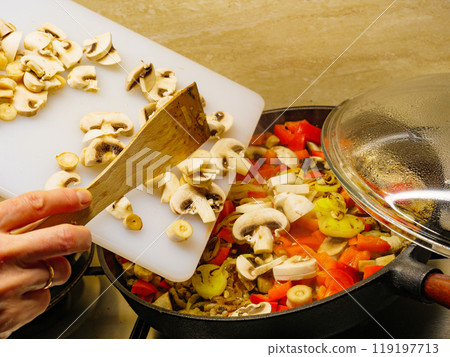 Adding mushrooms to pan vegetables. Adding mushrooms to pan vegetables. 119197713