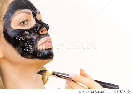 Woman applying black mask to skin face Woman applying black mask to skin face 119197800