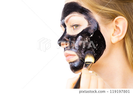 Woman applying black mask to skin face Woman applying black mask to skin face 119197801