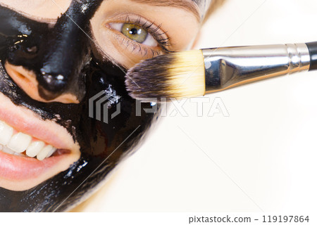 Woman applying black mud mask to face Woman applying black mud mask to face 119197864